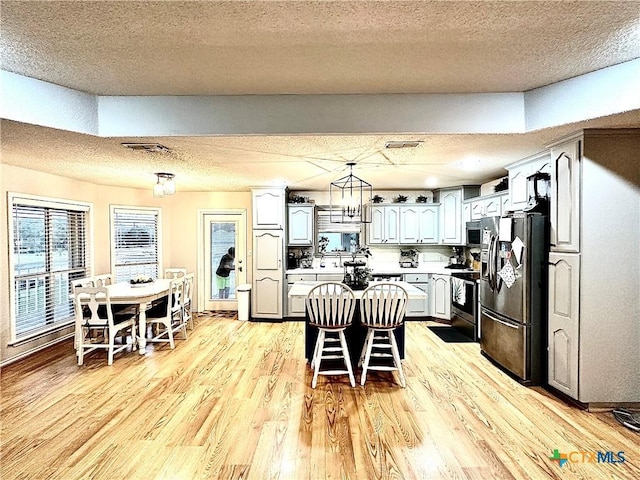 kitchen featuring a center island, a breakfast bar area, light hardwood / wood-style flooring, a textured ceiling, and stainless steel appliances