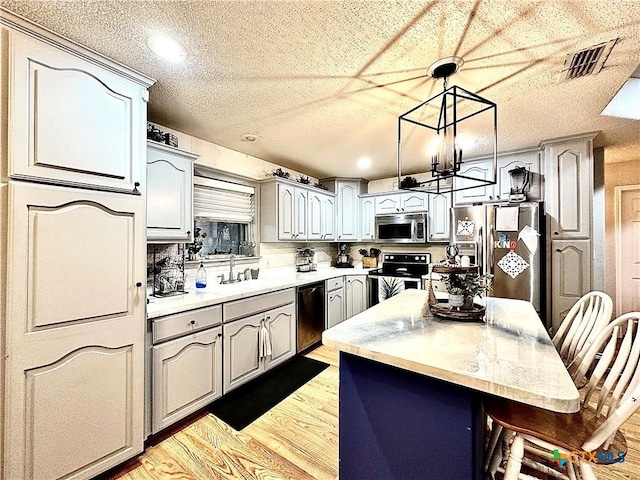 kitchen with pendant lighting, a center island, backsplash, light hardwood / wood-style flooring, and appliances with stainless steel finishes