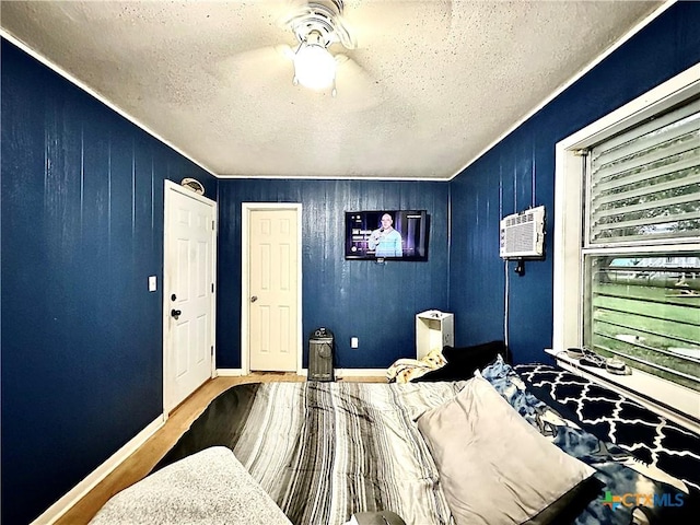 bedroom featuring an AC wall unit, wooden walls, and a textured ceiling