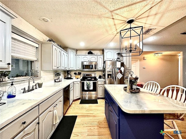 kitchen featuring a center island, decorative light fixtures, a breakfast bar area, appliances with stainless steel finishes, and light wood-type flooring