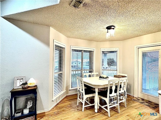 dining space featuring a textured ceiling and light hardwood / wood-style flooring