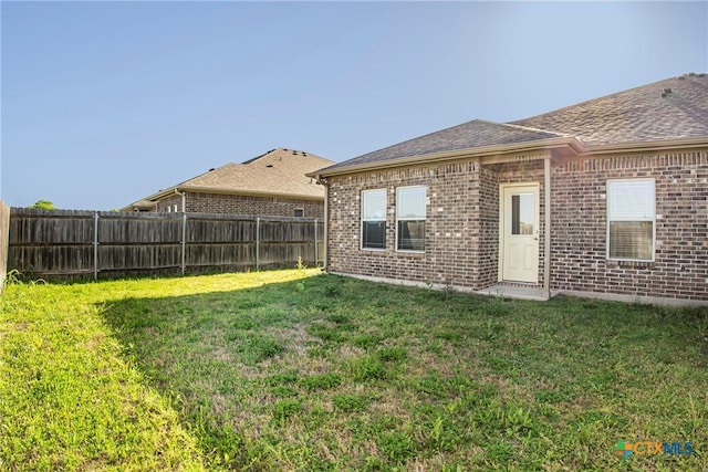 1121 Swanflower Ln, Temple, TX 76502 - rear view of property featuring brick siding, a lawn, a shingled roof, and a fenced backyard
