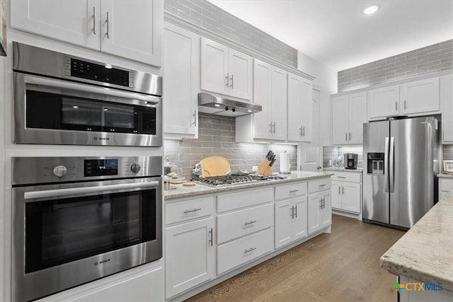119 Rivalto Dr, Horseshoe Bay, TX 78657 - kitchen featuring stainless steel appliances, under cabinet range hood, white cabinets, backsplash, and recessed lighting