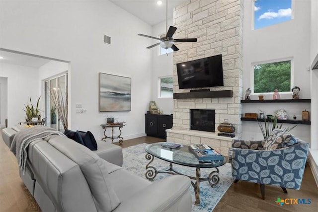 119 Rivalto Dr, Horseshoe Bay, TX 78657 - living area with a towering ceiling, wood finished floors, a ceiling fan, a stone fireplace, and baseboards