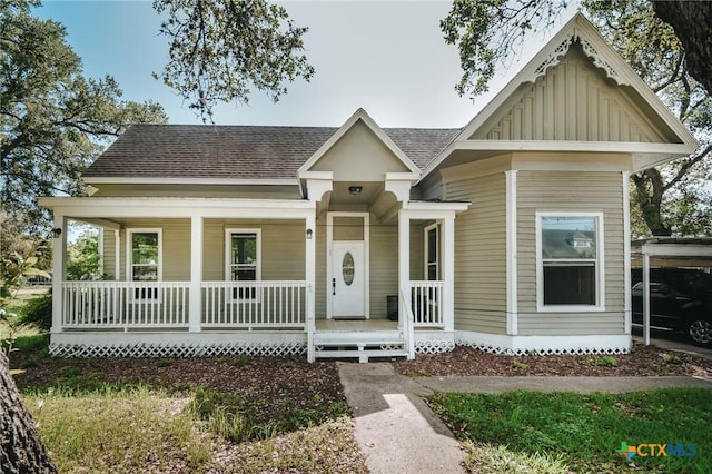view of front facade featuring roof with shingles, covered porch, and board and batten siding