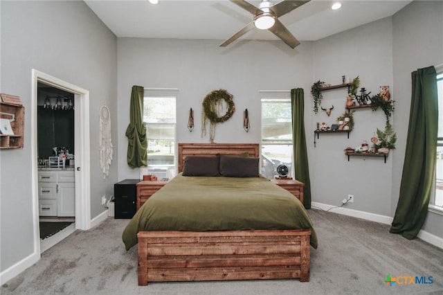 carpeted bedroom with baseboards, multiple windows, ensuite bath, and ceiling fan