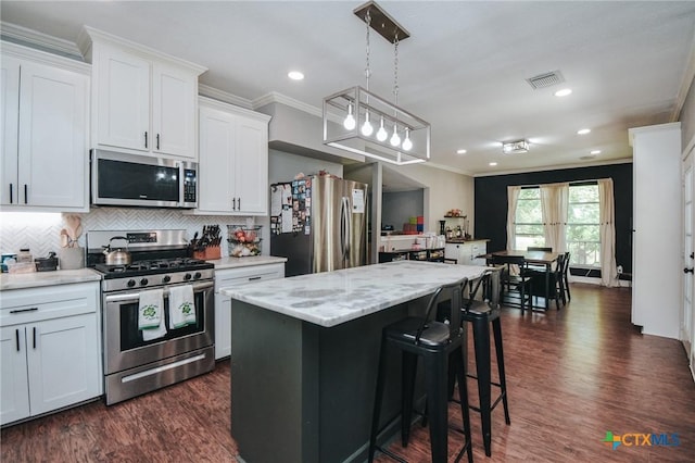 kitchen featuring white cabinets, stainless steel appliances, visible vents, and ornamental molding