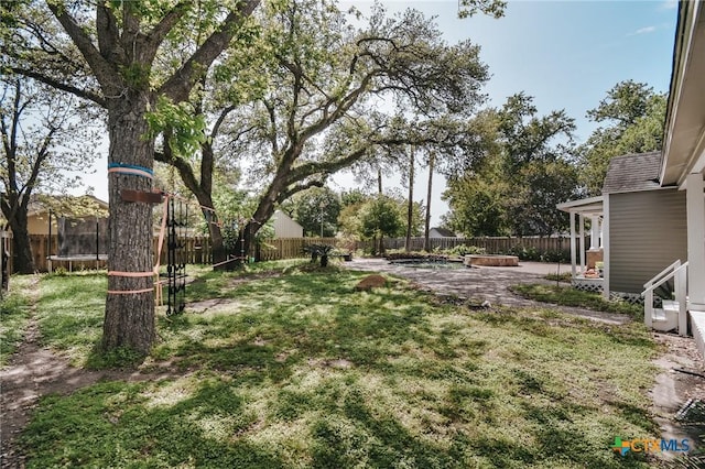 view of yard with a patio, a fenced backyard, and a trampoline