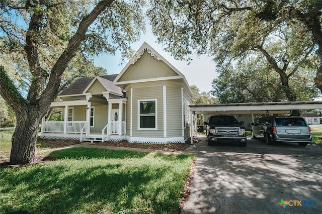 view of front facade with a porch, a front lawn, aphalt driveway, and a carport