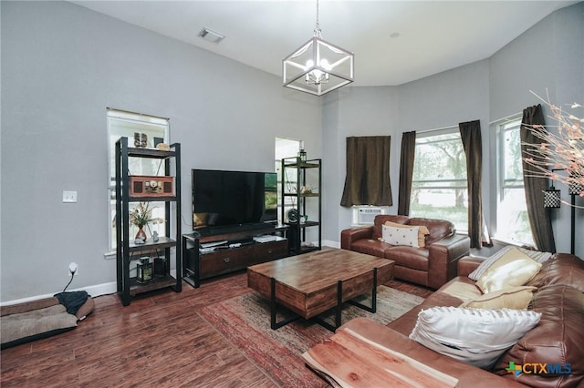 living room with visible vents, baseboards, wood finished floors, and an inviting chandelier