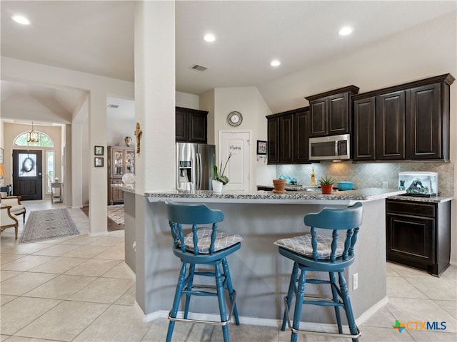 2136 Pioneer Pass, Seguin, TX 78155 - kitchen featuring appliances with stainless steel finishes, vaulted ceiling, a kitchen bar, decorative backsplash, and light tile patterned floors