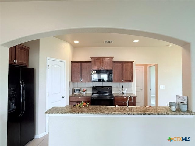 2602 Camp Cooper Dr, Killeen, TX 76549 - kitchen with black appliances, light stone countertops, arched walkways, a peninsula, and recessed lighting