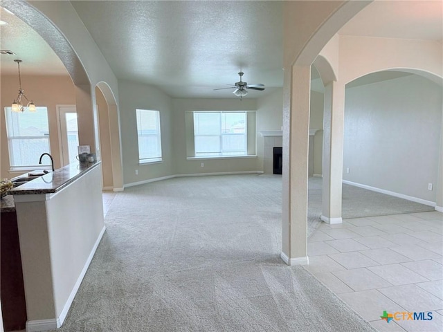 2602 Camp Cooper Dr, Killeen, TX 76549 - unfurnished living room featuring ceiling fan, light colored carpet, a textured ceiling, baseboards, and a tile fireplace