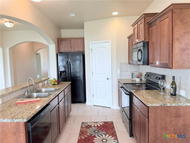 2602 Camp Cooper Dr, Killeen, TX 76549 - kitchen with black appliances, a sink, arched walkways, light stone counters, and brown cabinetry