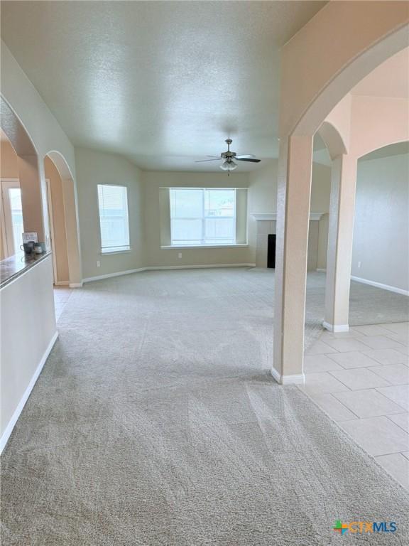 2602 Camp Cooper Dr, Killeen, TX 76549 - unfurnished living room featuring ceiling fan, healthy amount of natural light, baseboards, and a textured ceiling