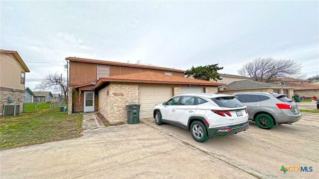 view of front facade featuring a garage, cooling unit, and a front lawn