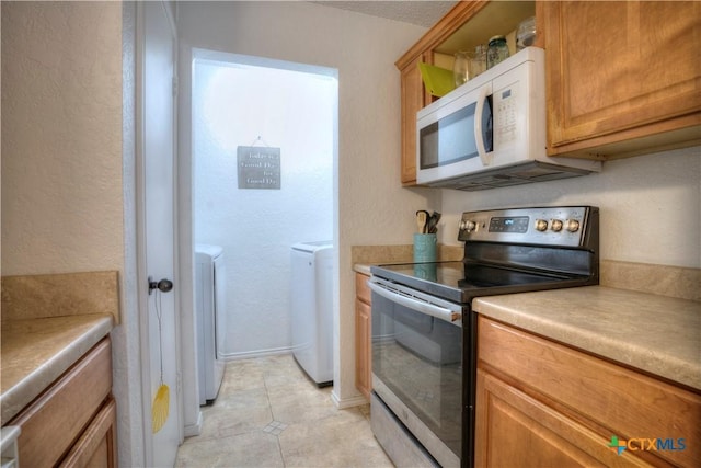 5110 Sam Houston, Temple, TX 76502 - kitchen featuring electric stove, white microwave, washer and dryer, light tile patterned flooring, and light countertops