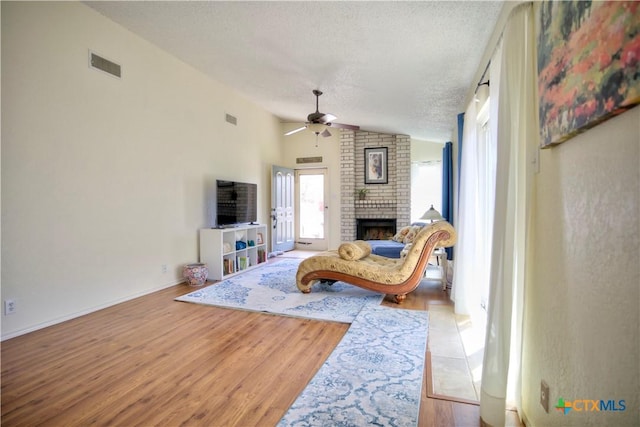 5110 Sam Houston, Temple, TX 76502 - living room featuring a textured ceiling, a ceiling fan, vaulted ceiling, wood finished floors, and a fireplace