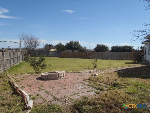 view of yard featuring a patio area, a fenced backyard, and a fire pit