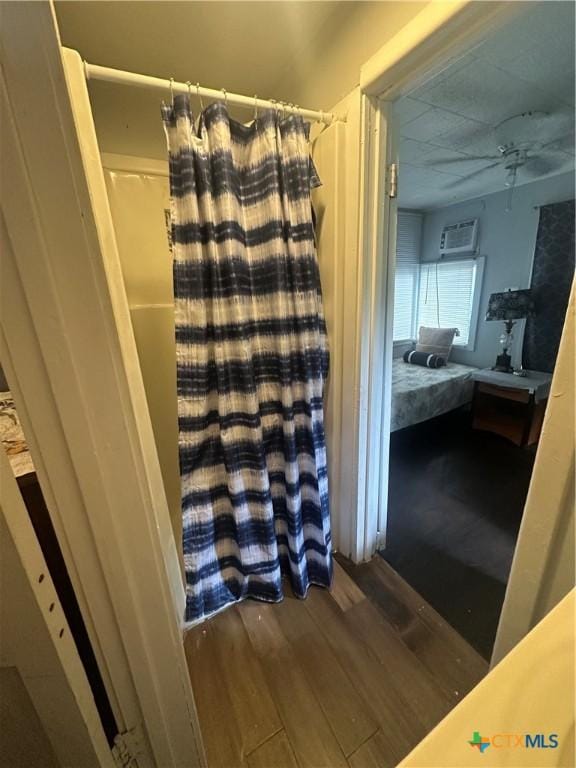 502 Tommy Dr, Port Lavaca, TX 77979 - full bathroom with wood finished floors, ceiling fan, curtained shower, and a wall unit AC