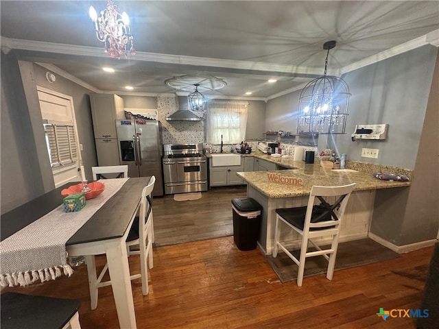 502 Tommy Dr, Port Lavaca, TX 77979 - kitchen with appliances with stainless steel finishes, a chandelier, crown molding, wall chimney range hood, and a peninsula