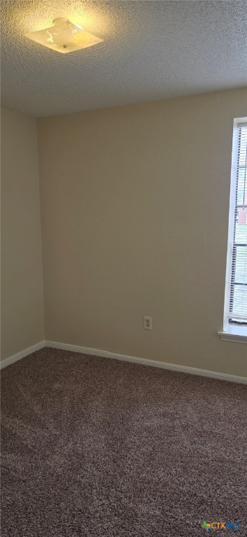 carpeted empty room featuring baseboards and a textured ceiling