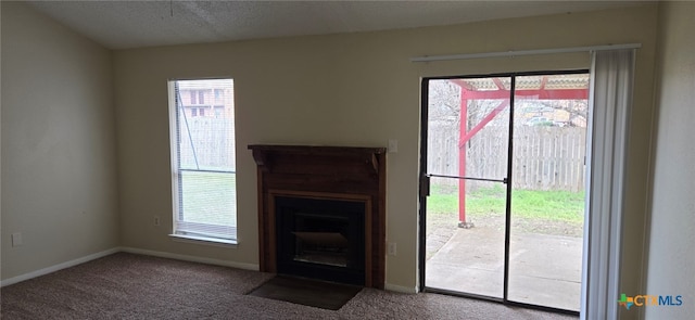 unfurnished living room featuring a fireplace with flush hearth, carpet flooring, a textured ceiling, and baseboards