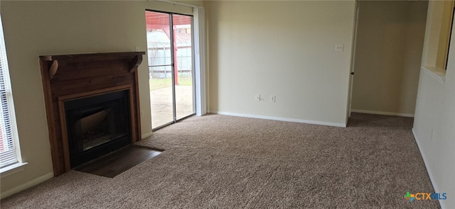 unfurnished living room with a fireplace with flush hearth, carpet, and baseboards