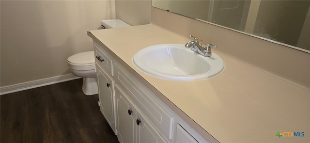 half bath featuring vanity, toilet, wood finished floors, and baseboards