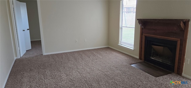 unfurnished living room featuring baseboards, carpet floors, and a fireplace with flush hearth