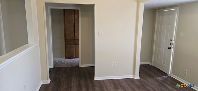 hallway with dark wood-type flooring and baseboards