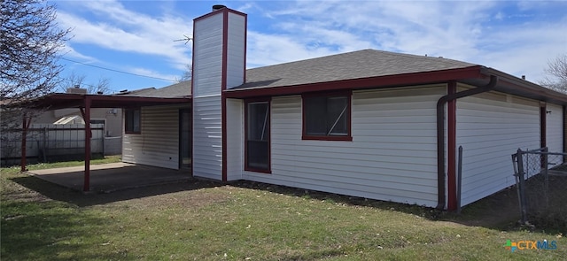 rear view of property with a lawn, roof with shingles, a patio, and fence