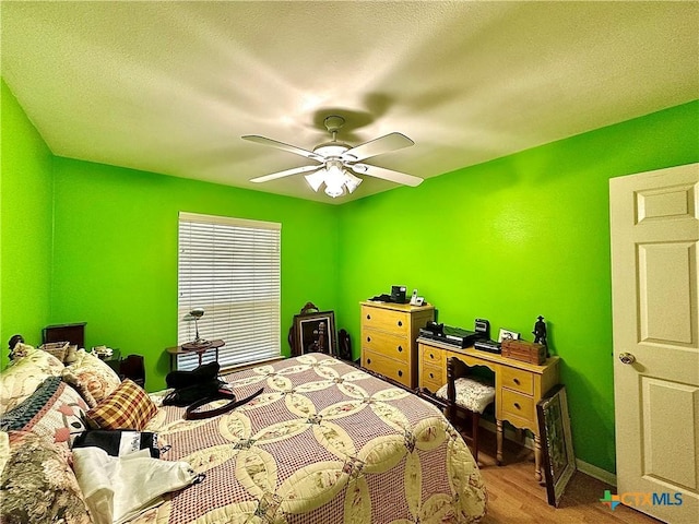 bedroom with baseboards, a ceiling fan, wood finished floors, and a textured ceiling
