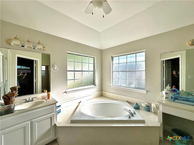 bathroom featuring a ceiling fan, vanity, vaulted ceiling, and a garden tub