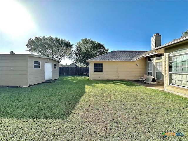 view of yard with fence and an outbuilding