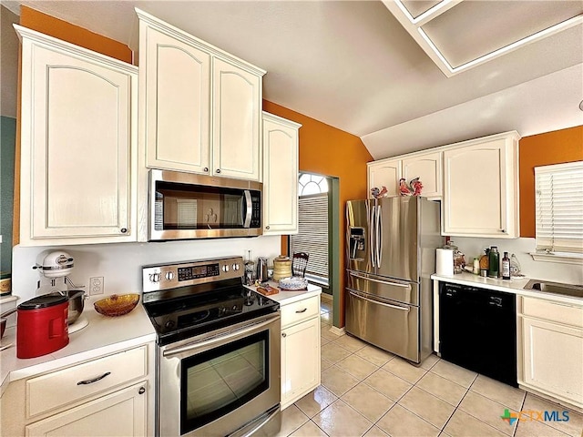 kitchen with vaulted ceiling, light tile patterned floors, light countertops, white cabinets, and stainless steel appliances