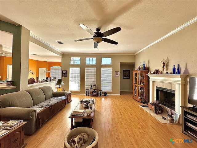 living area with visible vents, a ceiling fan, crown molding, and wood finished floors