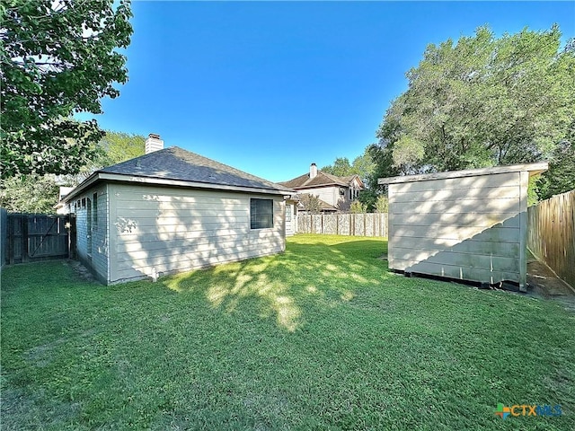 view of yard featuring an outbuilding, a fenced backyard, and a storage unit