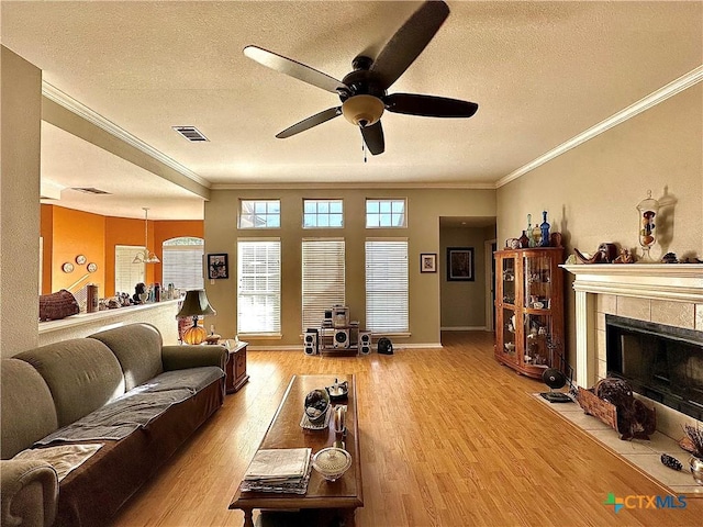 living room featuring visible vents, light wood-type flooring, ornamental molding, and ceiling fan