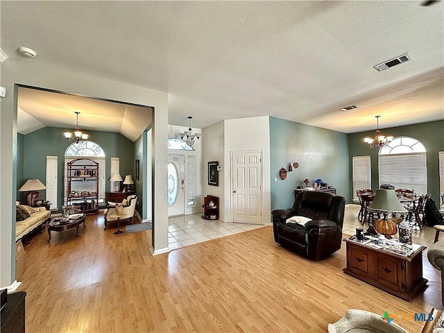 living room featuring visible vents, light wood-type flooring, an inviting chandelier, and a textured ceiling
