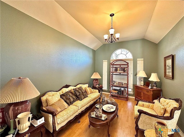 sitting room featuring baseboards, wood finished floors, a notable chandelier, and lofted ceiling