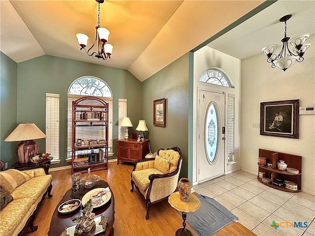 foyer featuring a chandelier, wood finished floors, baseboards, and lofted ceiling