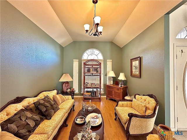 living area with a chandelier, lofted ceiling, and wood finished floors