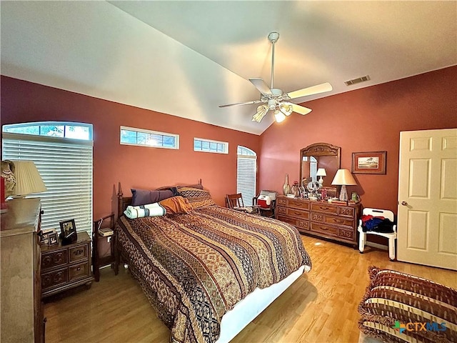 bedroom featuring visible vents, multiple windows, wood finished floors, and lofted ceiling