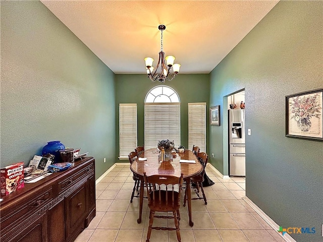 dining room with a textured wall, a notable chandelier, baseboards, and light tile patterned flooring