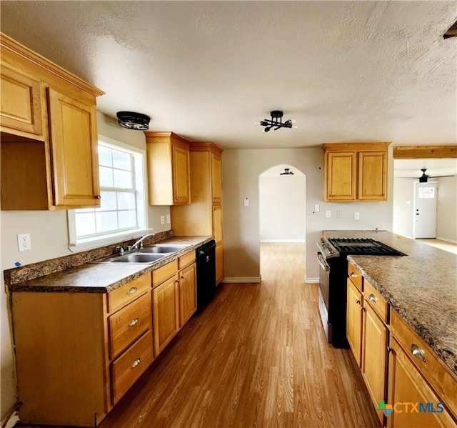 kitchen featuring a textured ceiling, stainless steel range with gas stovetop, black dishwasher, baseboards, and dark wood-style flooring