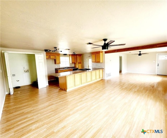 kitchen featuring a textured ceiling, light wood-type flooring, a peninsula, and open floor plan