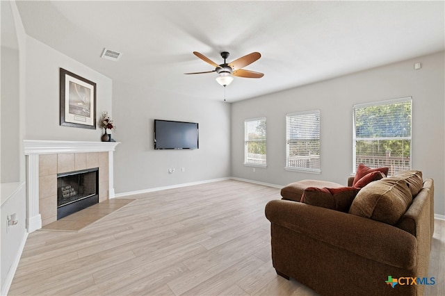 living room featuring ceiling fan, a fireplace, and light wood-type flooring