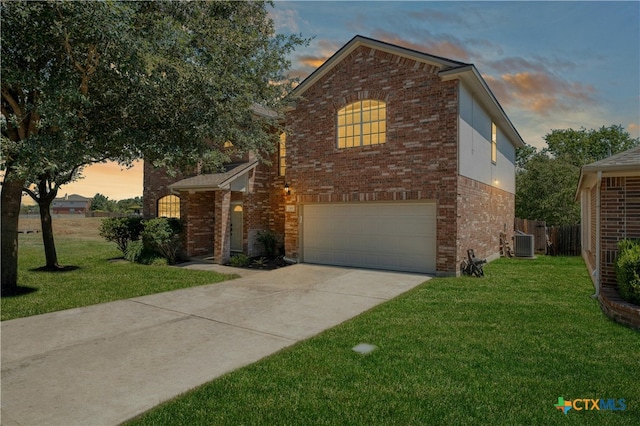 view of front property featuring a lawn, a garage, and central air condition unit