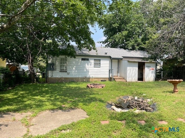 rear view of house featuring a yard and a fire pit